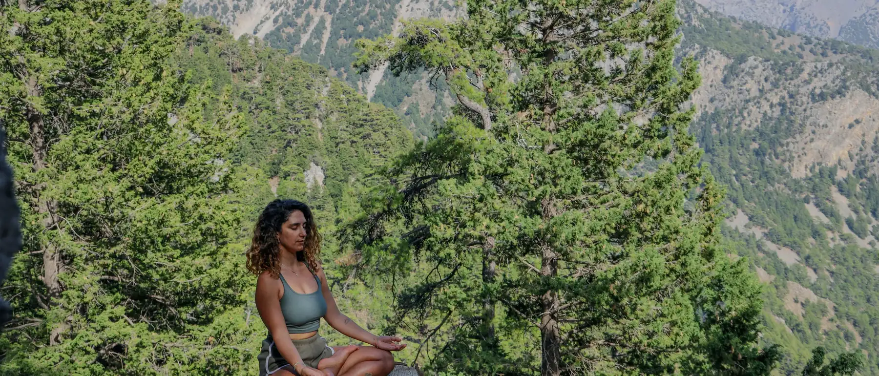 Mujer sentada en meditación en un bosque de montaña
